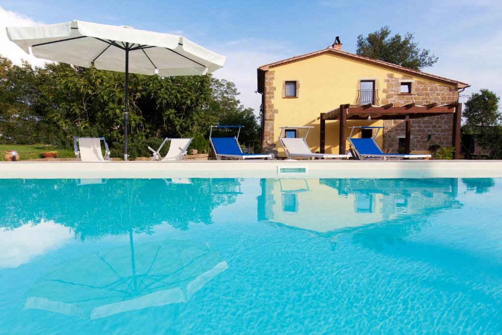 une piscine avec des chaises et un parasol ainsi qu'une maison dans l'établissement FicOlivo, à Pitigliano