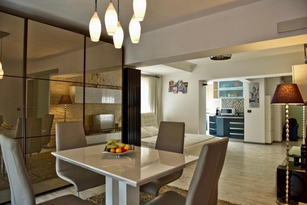 een eetkamer en een woonkamer met een witte tafel en stoelen bij Eric Apartment 100 in Boekarest