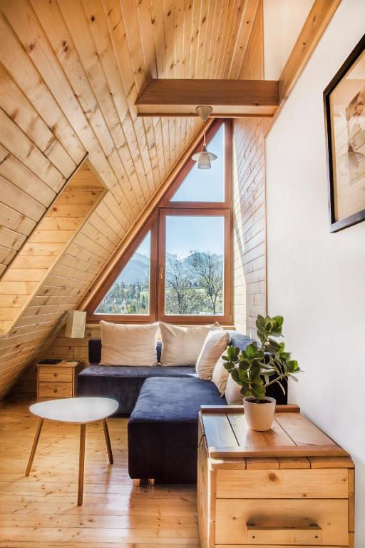 a living room with a blue couch and a large window at Apartament Olczanka Zakopane in Zakopane