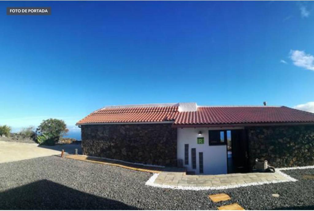 um pequeno edifício branco com um telhado vermelho em La Casa del Risco em El Pinar del Hierro