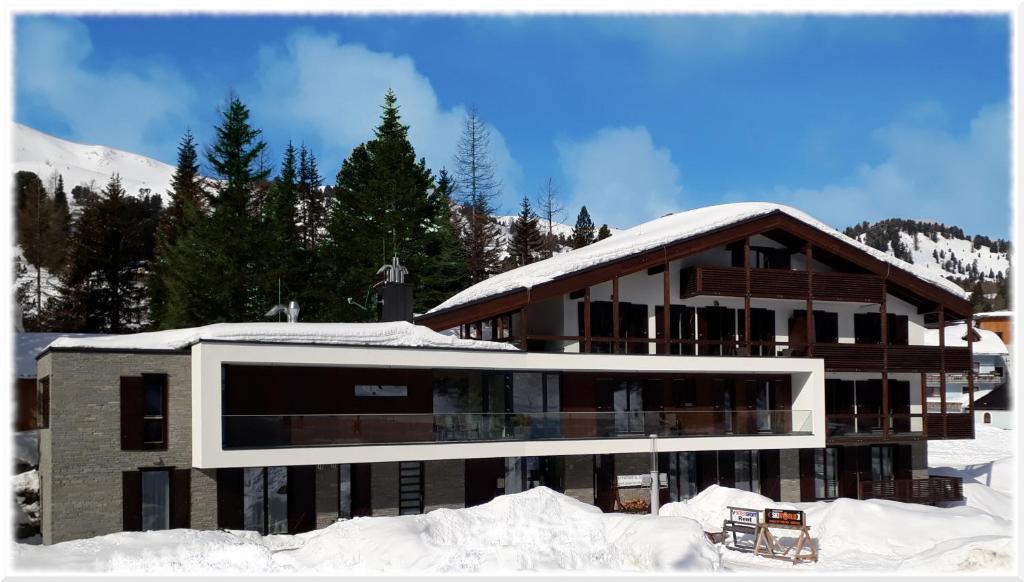 un gran edificio con nieve en el suelo en Apparthotel Silbersee en Turracher Hohe