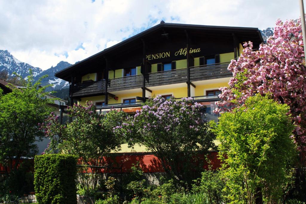 
a large building with a balcony and trees at Café Pension Alpina in Innsbruck
