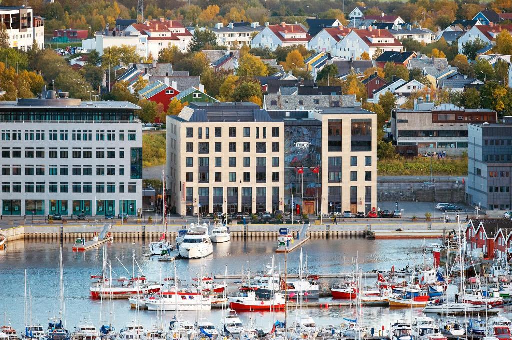 een groep boten aangemeerd in een haven in een stad bij Thon Hotel Nordlys in Bodø