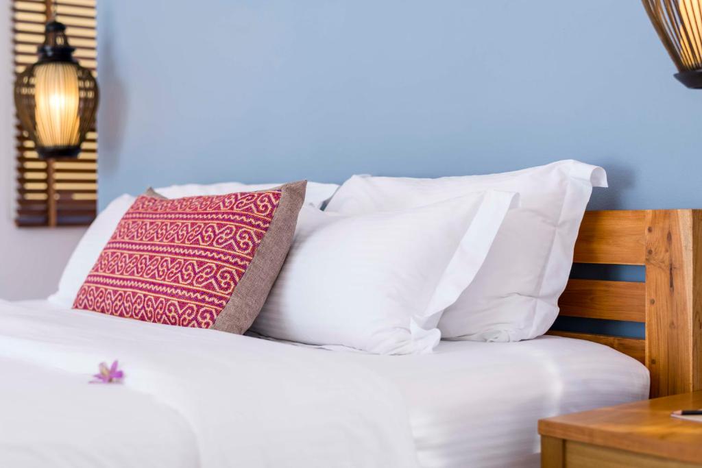 a bed with white pillows and a pink pillow at Krabi Home Resort in Tab Kaek Beach