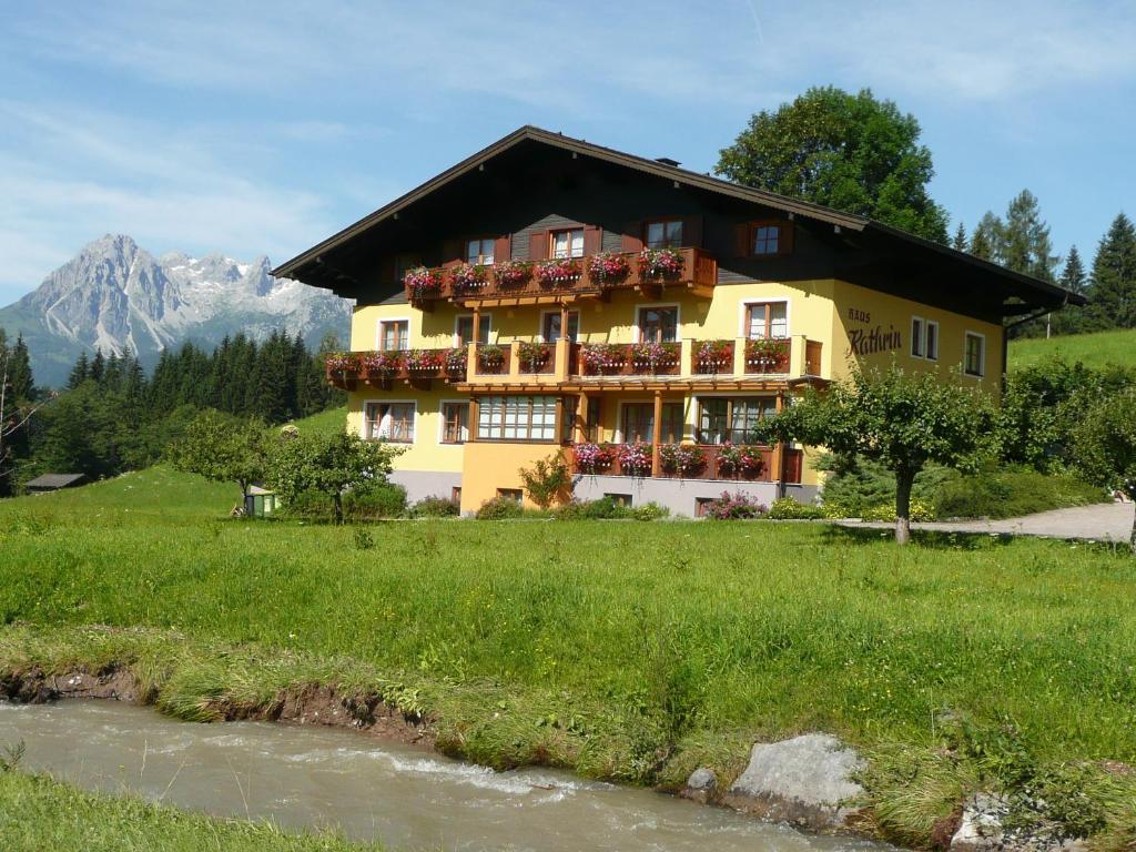 a large yellow building with balconies and a river at Haus Kathrin in Werfenweng