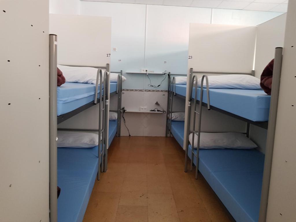 a room with three bunk beds and a hallway at Albergue A Ponte Ribadeo in Ribadeo