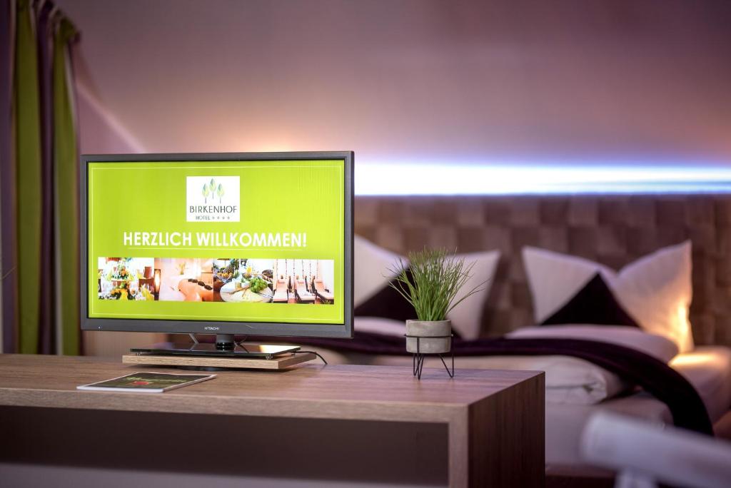 einen TV auf einem Tisch in einem Schlafzimmer in der Unterkunft Hotel-Restaurant Birkenhof in Bad Soden-Salmünster
