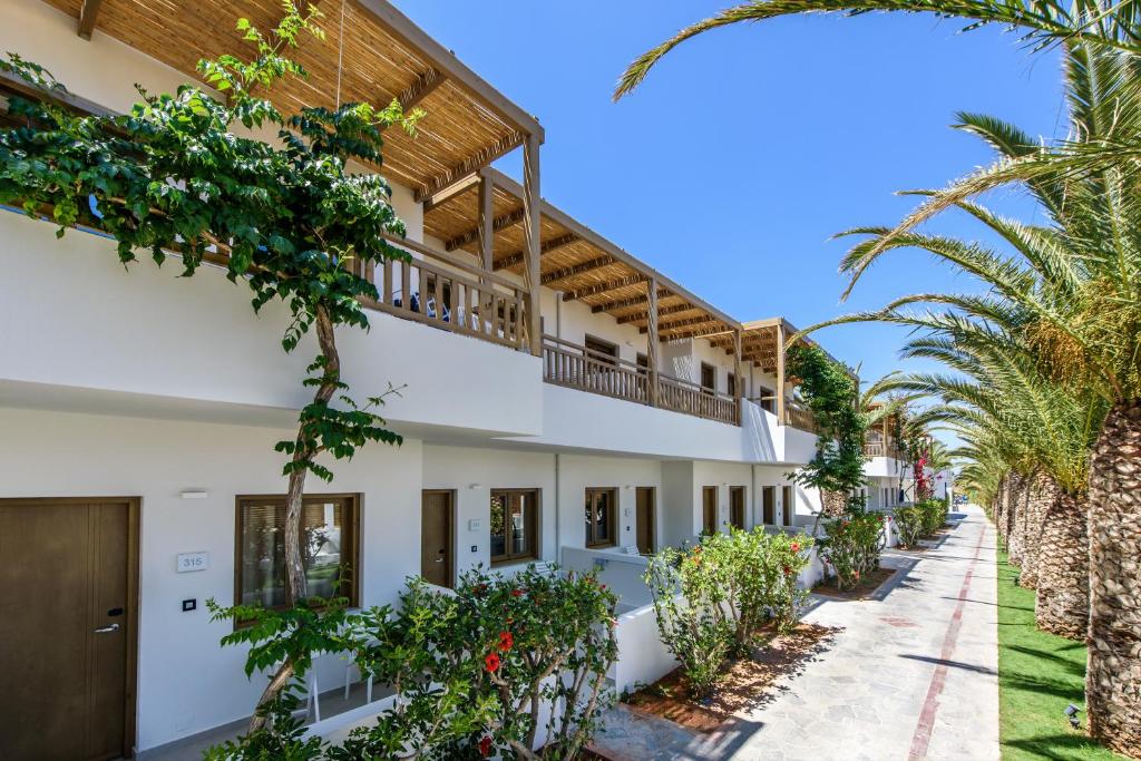 an exterior view of a building with palm trees at Stella Village Seaside Hotel in Hersonissos