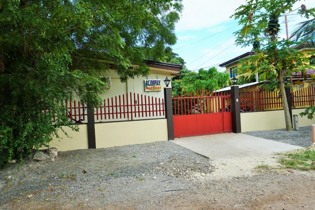 un garage con una porta rossa e una recinzione di Alimpay Foresters Apartment a Panglao