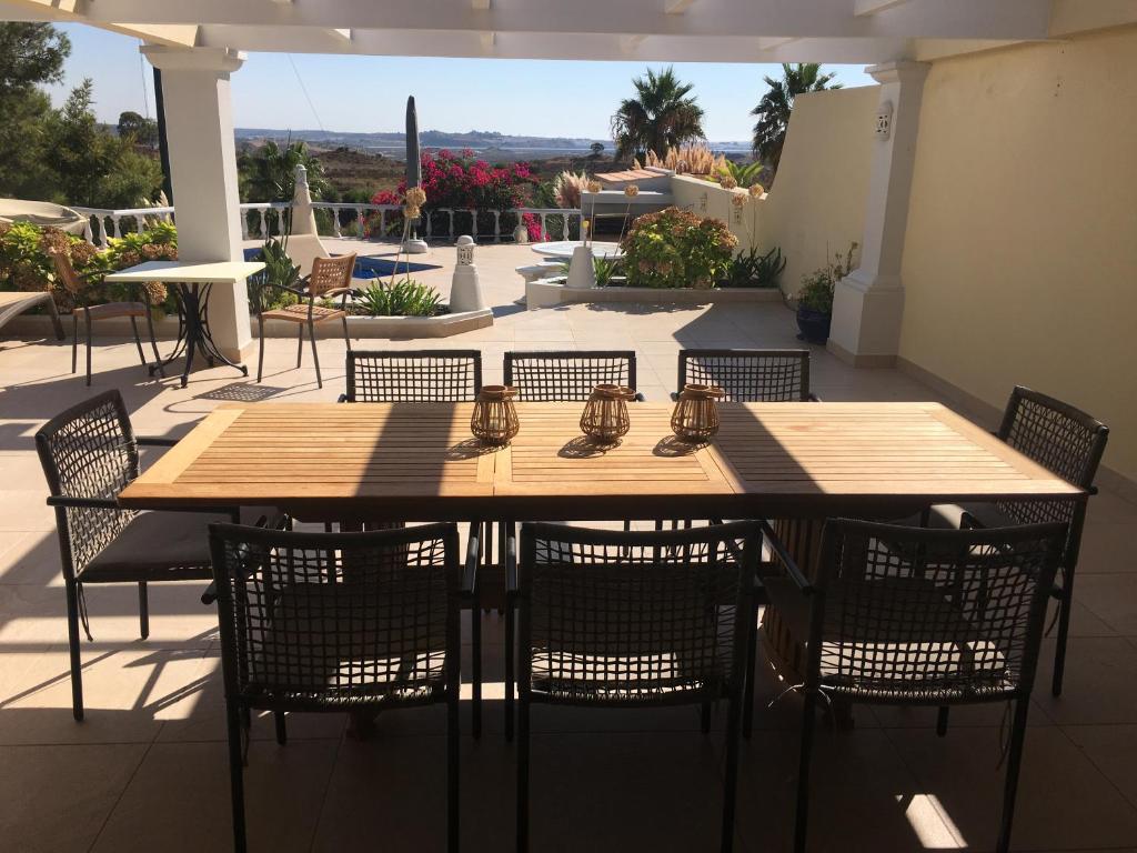 een houten tafel en stoelen op een patio bij Villa Ponte Vista in Castro Marim