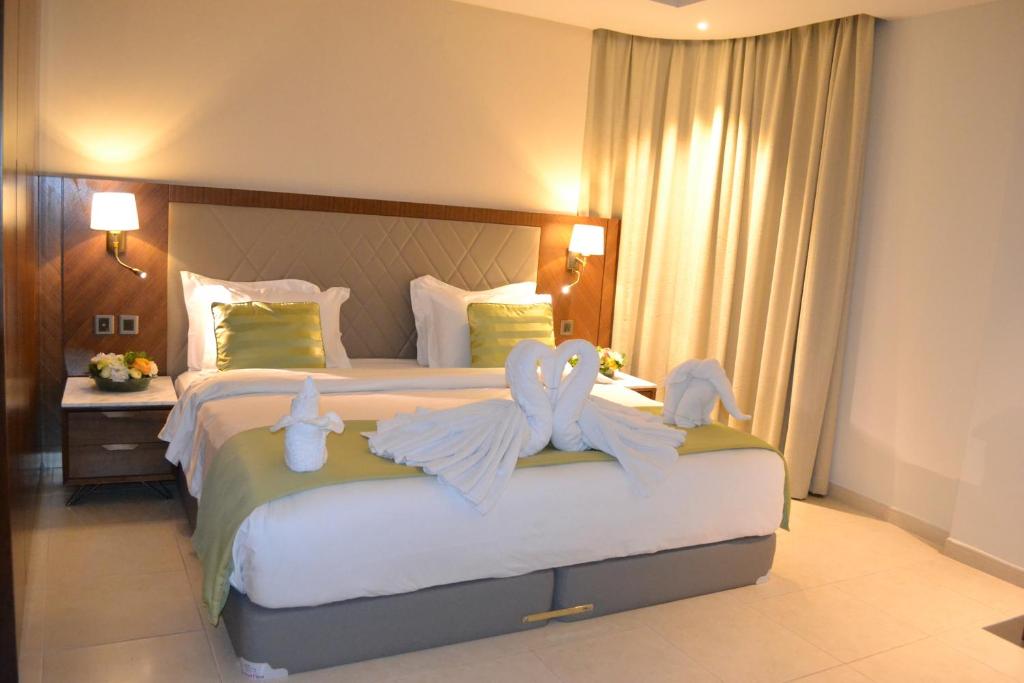 فندق قصر رامي في المنامة: غرفة نوم مع سرير كبير مع مناشف الحيوانات عليه