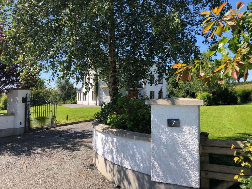 een stenen muur met een boom op een kerkhof bij The White House in Enniskillen