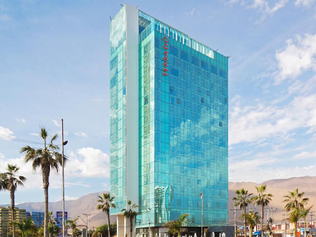 a tall glass building with palm trees in front of it at Hotel Terrado Cavancha in Iquique
