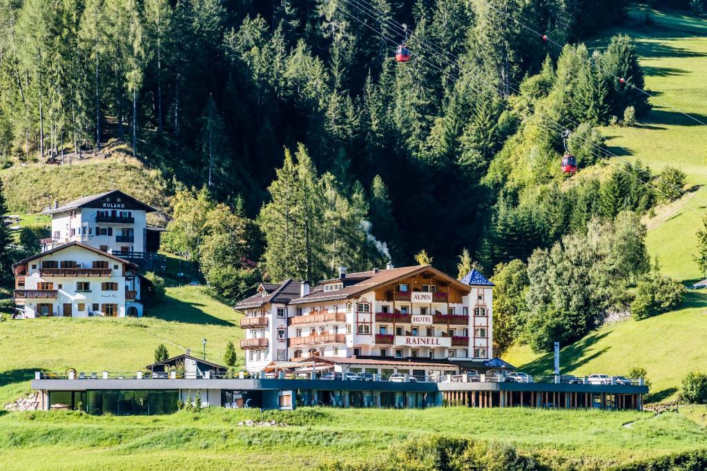 a hotel on a hill in a green field at Rainell Dolomites Retreat in Ortisei