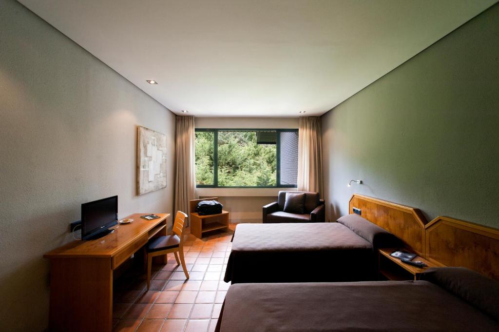 Habitación de hotel con 2 camas, escritorio y TV. en AS Hoteles Altube, en Zuia