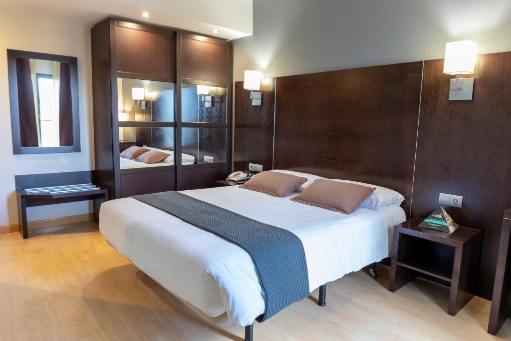 a bedroom with a large bed with a wooden headboard at Hotel Alda Cardeña in Burgos