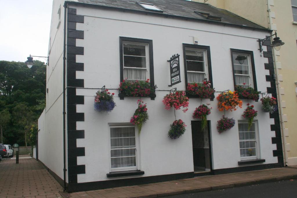 a white building with flowers on the side of it at Riverside B&B in Cushendall