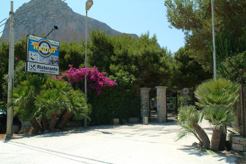 a sign for a resort with a mountain in the background at Camping Village La Pineta in San Vito lo Capo
