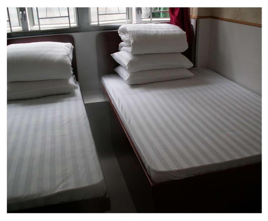 2 camas en un tren con sábanas y almohadas blancas en Lung Wa Hotel, en Hong Kong