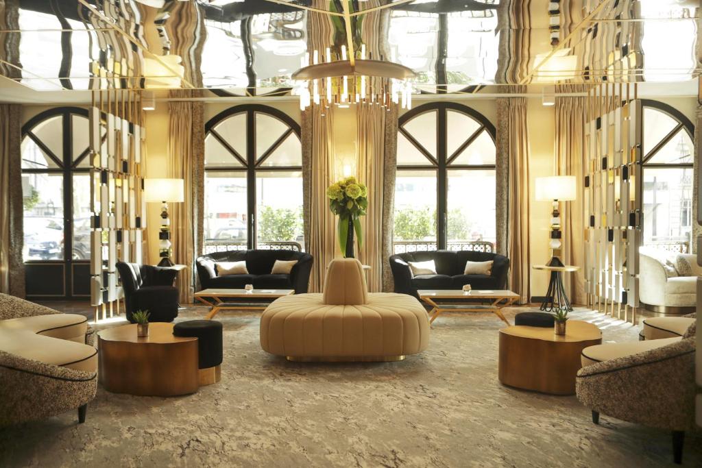 a large lobby with couches and chairs and a chandelier at Hôtel le Derby Alma by Inwood Hotels in Paris