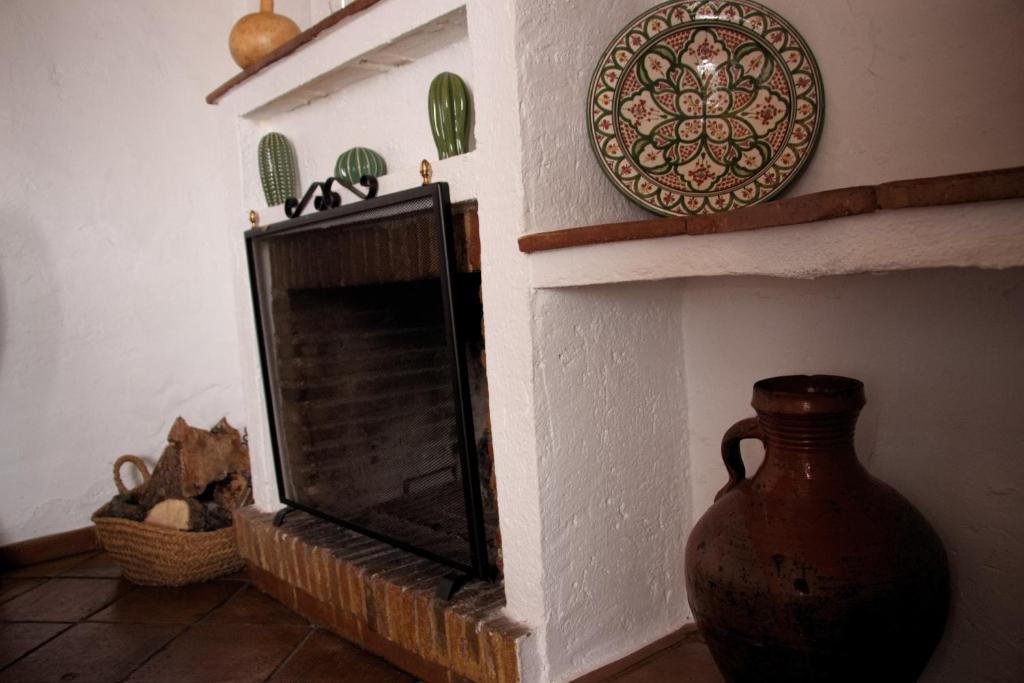 a fireplace with a vase and a plate on a wall at La Carrihuela in Algodonales