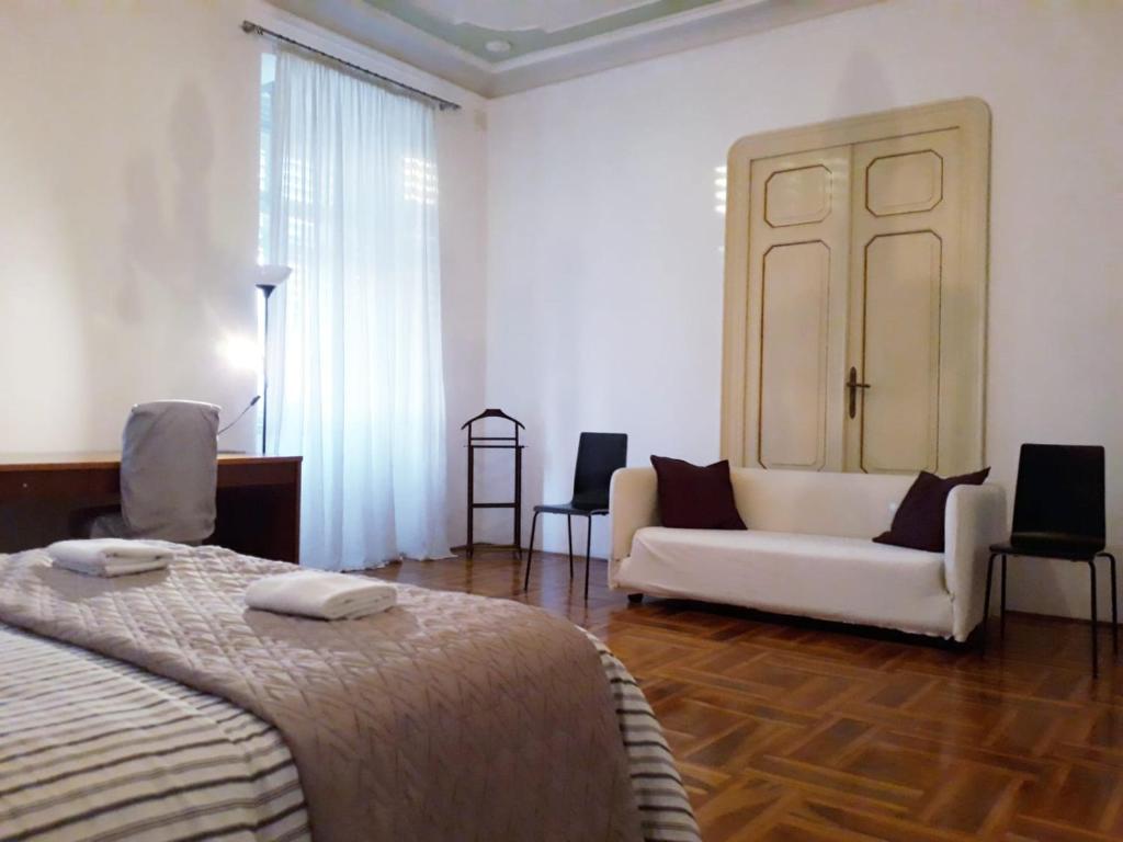 a bedroom with a white bed and a couch at Agli incanti in Trieste
