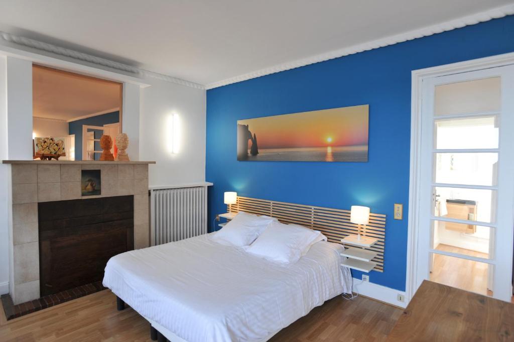 a bedroom with a white bed and a blue wall at Gîte de la Plage in Étretat