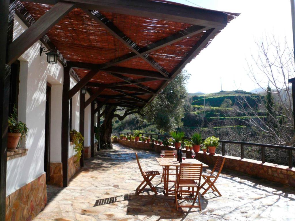 patio con tavolo e sedie sotto un tetto di Cortijo Pilongo a Monachil