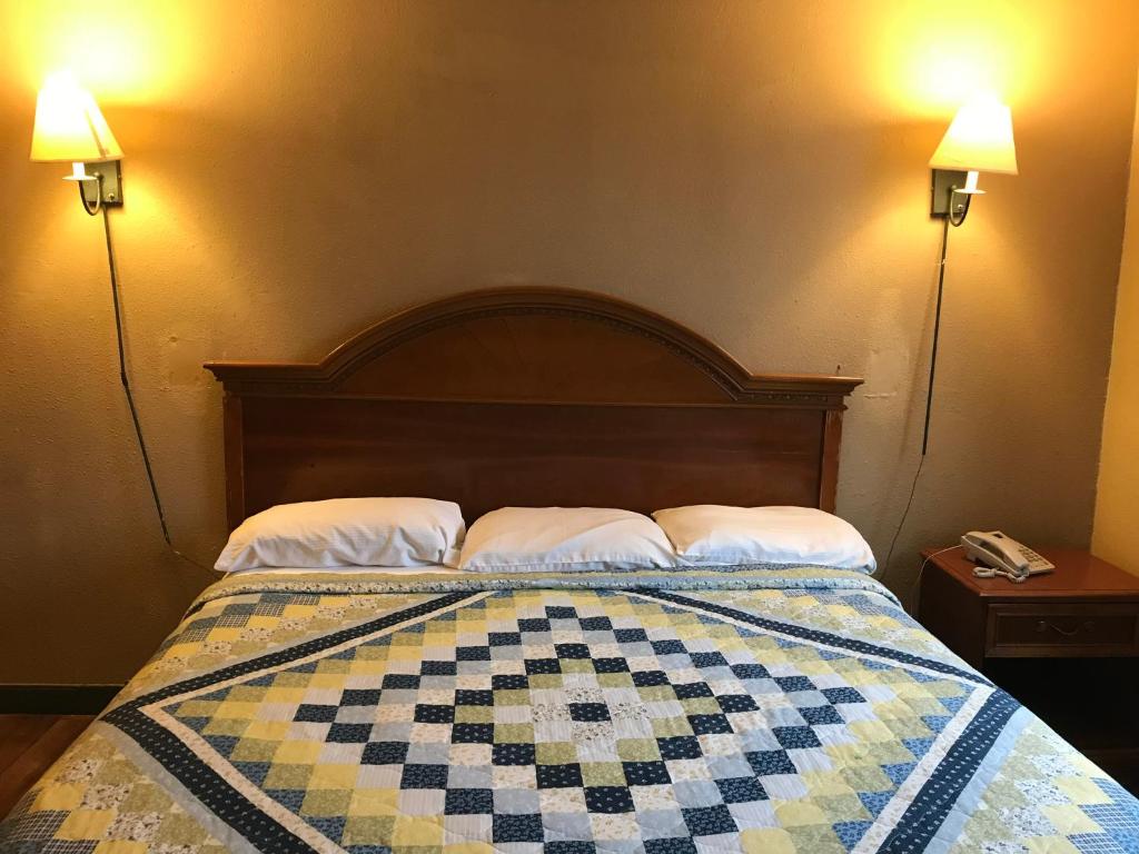 a bedroom with a bed with a checkered quilt at Economy Inn in Fort Wayne