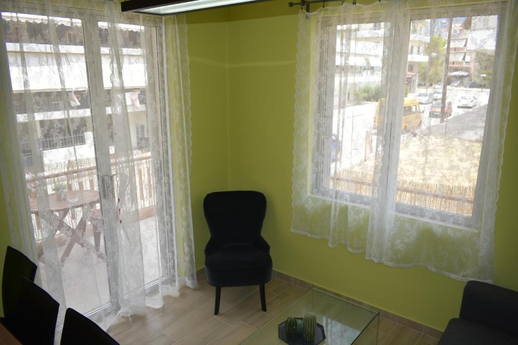 een stoel in een kamer met groene muren en ramen bij APARTMENT ALEXANDRA in Nafplio