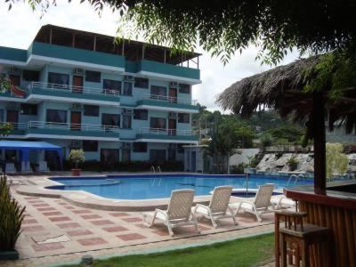 uma piscina com cadeiras e um grande edifício em Siona Hotel em Atacames