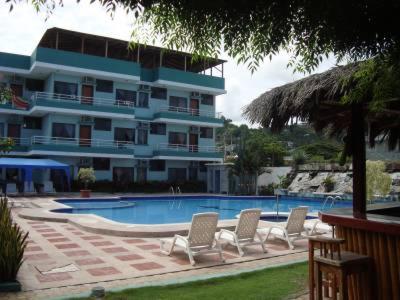 a swimming pool with chairs and a large building at Siona Hotel in Atacames