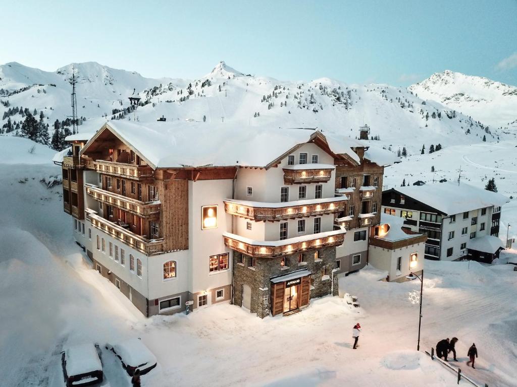 a building in the snow with people standing around it at Hotel Alpenland in Obertauern