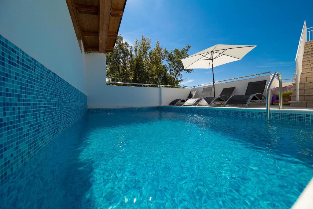 een zwembad met stoelen en een parasol bij Apartment Miric in Crikvenica