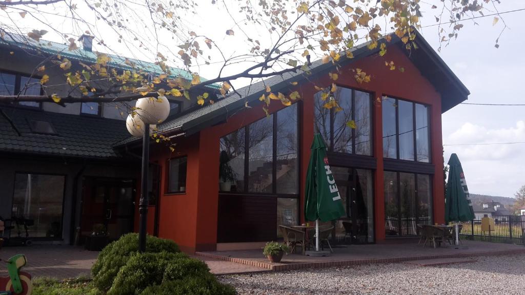 a red building with a flag in front of it at Bed & Breakfast Green Roof in Rybarzowice