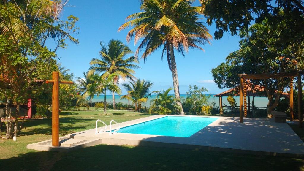 una piscina en un patio con palmeras en Vista Linda Cumuruxatiba, en Cumuruxatiba
