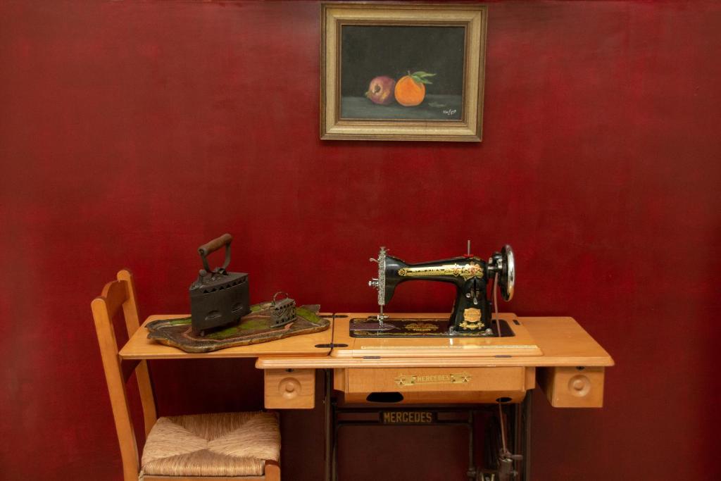 a sewing machine sitting on a wooden table against a red wall at 3 Brothers II - Vintage - Μια άλλη εποχή in Tríkala