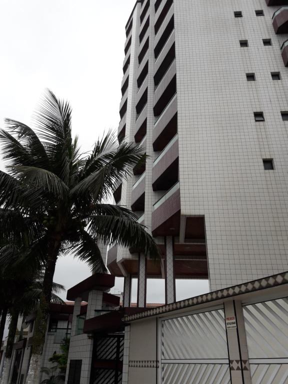 ein hohes Gebäude mit einer Palme davor in der Unterkunft Apartamento inteiro in Praia Grande