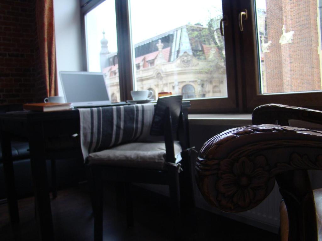 une table avec un ordinateur portable et une chaise devant une fenêtre dans l'établissement St. Dorothys hostel - apartments, à Wrocław