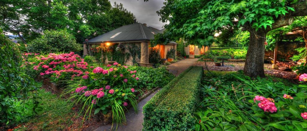 un giardino con fiori rosa e gazebo di Old WesleyDale Heritage Accommodation a Mole Creek