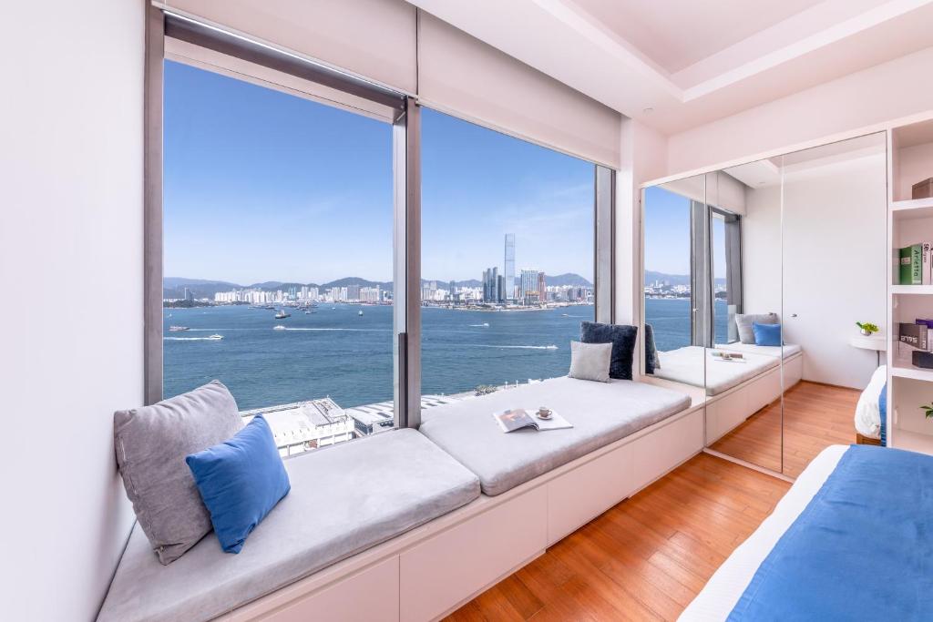 uma sala de estar com um sofá grande e janelas grandes em The Connaught em Hong Kong