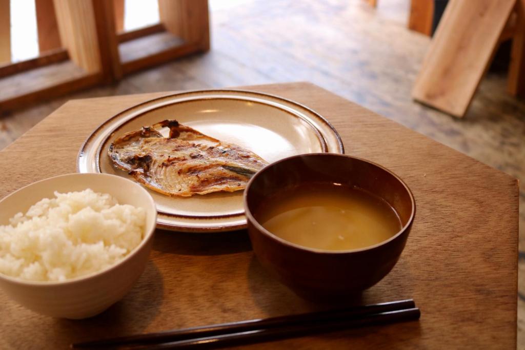 a table with a plate of food and a bowl of rice at Guest House MARUYA in Atami