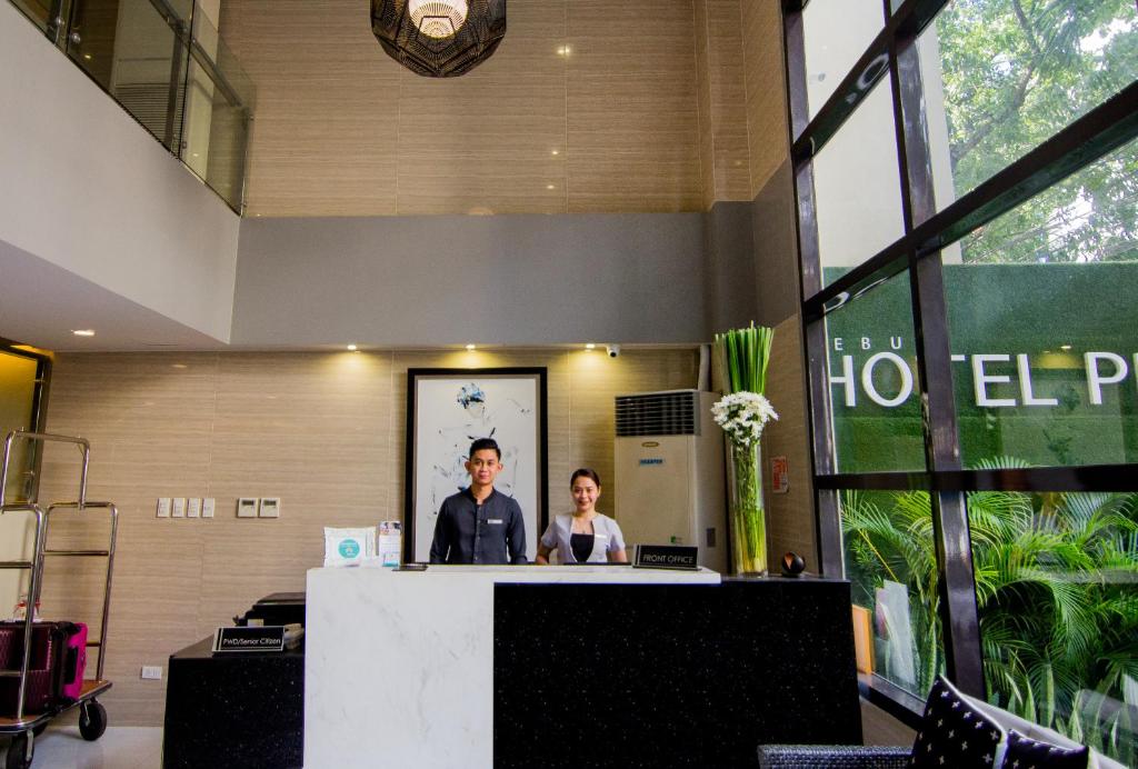 a man and a woman standing at a reception desk at Cebu Hotel Plus in Cebu City