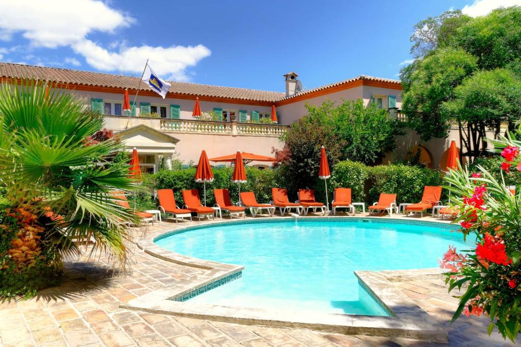 uma piscina com cadeiras e guarda-sóis num resort em Best Western L'Orangerie em Nîmes