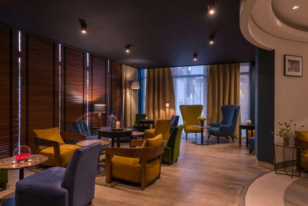 een wachtkamer met stoelen, tafels en ramen bij Best Western Hotel le Galice Aix-en-Provence in Aix-en-Provence