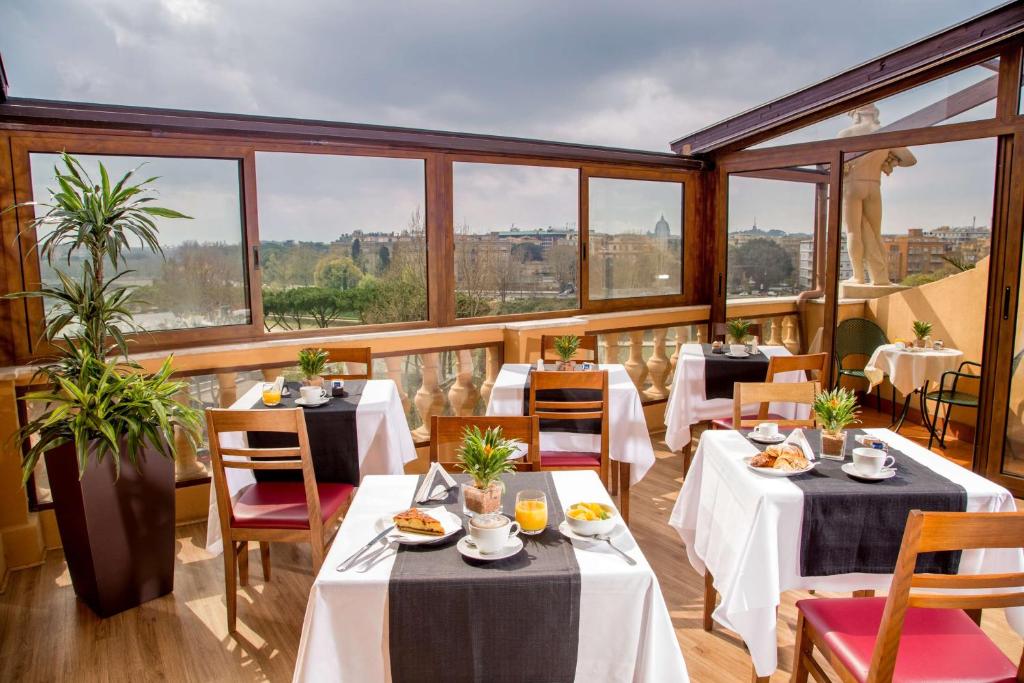 ein Restaurant mit Tischen, Stühlen und Fenstern in der Unterkunft Best Western Hotel Astrid in Rom