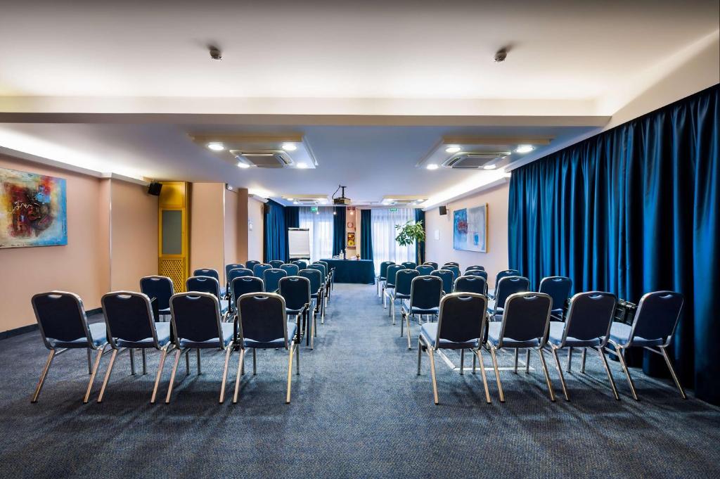 szereg krzeseł w pokoju z niebieskimi zasłonami w obiekcie Best Western Hotel Mediterraneo w Katanii