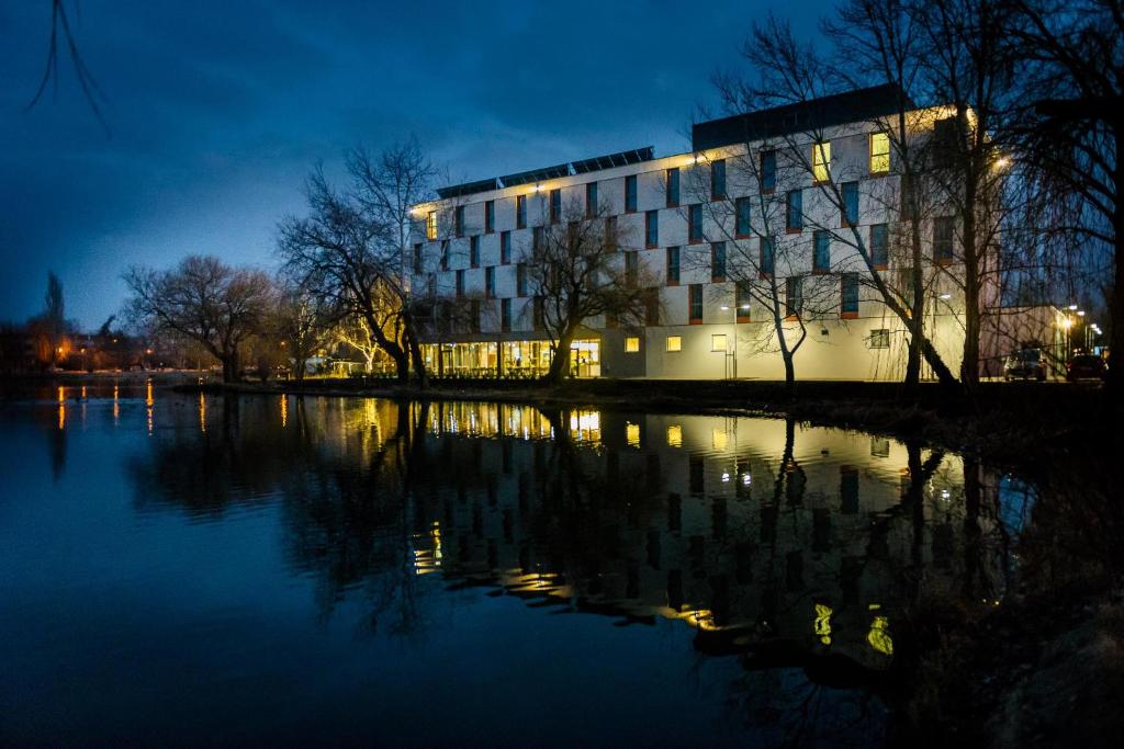 a building next to a body of water at night at Best Western Plus Lakeside Hotel in Székesfehérvár