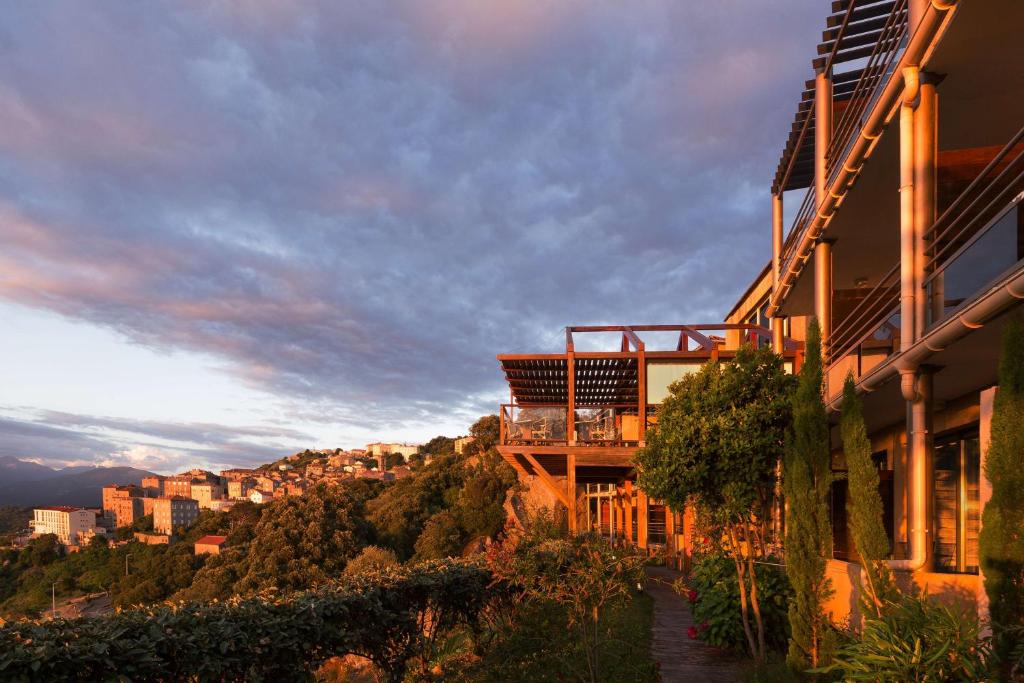 a building on a hill with a city in the background at Best Western Plus San Damianu in Sartène