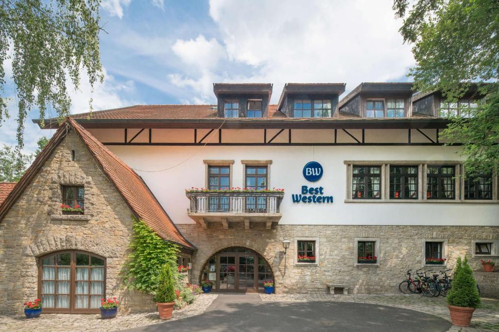 ein großes Steingebäude mit Balkon oben in der Unterkunft Best Western Hotel Polisina in Ochsenfurt